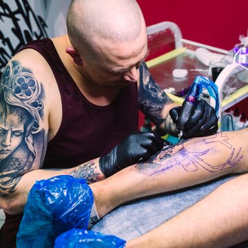 tattoo master painting leg with machine 23 2147834053 تاتو به کدام اندام ها آسیب بیشتری می زند؟